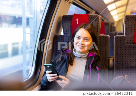 Woman using her smartphone while traveling by train Woman using her smartphone while traveling by train 86452311