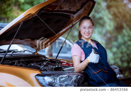 Woman car mechanic wearing glass and glove open car hood repairing check car problem system check detail for maintenance and fixed in car garage. 86453566