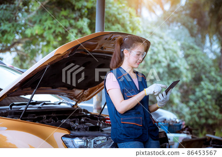 Woman car mechanic wearing glass and glove open car hood repairing check car problem system check detail for maintenance and fixed in car garage. Woman car mechanic wearing glass and glove open car hood repairing check car problem system check detail for maintenance and fixed in car garage. 86453567