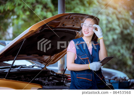 Woman car mechanic wearing glass and glove open car hood repairing check car problem system check detail for maintenance and fixed in car garage. 86453568
