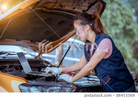 Woman car mechanic wearing glass and glove open car hood repairing check car problem system check detail for maintenance and fixed in car garage. Woman car mechanic wearing glass and glove open car hood repairing check car problem system check detail for maintenance and fixed in car garage. 86453569