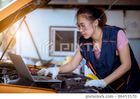Woman car mechanic wearing glass and glove open car hood repairing check car problem system check detail for maintenance and fixed in car garage. 86453570