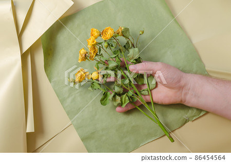 The man's right hand holds the fading flowers. 86454564