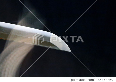 The tip of a Japanese sword that seems to emerge against a black background, and the refraction of light through the glass create a bewitching atmosphere. 86458269
