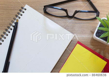 Notepad with yellow note, potted plant and study glasses. Flat lay Notepad with yellow note, potted plant and study glasses. Flat lay 86460636