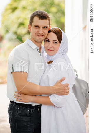 man and woman in headscarf and light-colored robes in the park by the trees. man and woman in headscarf and light-colored robes in the park by the trees. 86460829