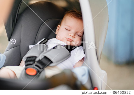 a little boy sleeps strapped in a stroller. a little boy sleeps strapped in a stroller. 86460832