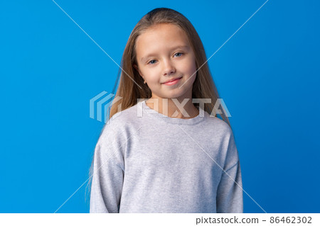 Pretty smiling girl portrait against blue background in studio Pretty smiling girl portrait against blue background in studio 86462302