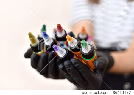 Woman master of tattooing holding bottles of colorful tattoo ink. 86463157