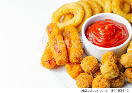 Southern fried and roast chicken bites, onion rings and mozzarella stick served on the white plate with tomato sauce 86465342