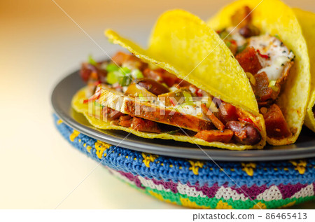 Mexican tacos shells with chicken and red kidney beans, onion,  red and green peppers, and salsa sauce 86465413