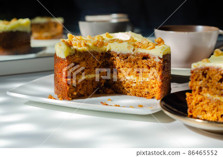 Sliced carrot cake filled and topped with cream cheese buttercream and decorated with walnuts 86465552