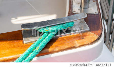 Dock cleat on the side of a boat in a small marina, an element of yachting equipment Dock cleat on the side of a boat in a small marina, an element of yachting equipment 86466171