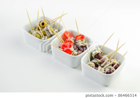 The traditional Spanish appetizers of olives, tomatoes and anchovies in a white ceramic bowls The traditional Spanish appetizers of olives, tomatoes and anchovies in a white ceramic bowls 86466314