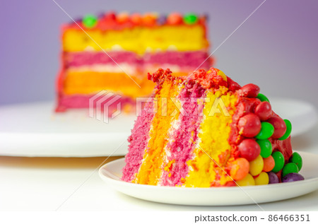 Rainbow celebration cake, coloured sponge cake filled and covered with frosting and hand decorated with chewy fruit candies in a crisp sugar shell with fruit flavour Rainbow celebration cake, coloured sponge cake filled and covered with frosting and hand decorated with chewy fruit candies in a crisp sugar shell with fruit flavour 86466351