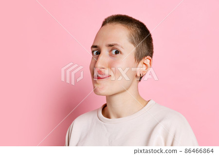 Funny young woman, student with short hair touching nose with tongue. isolated on pink background. Concept of emotions, studying, ad Funny young woman, student with short hair touching nose with tongue. isolated on pink background. Concept of emotions, studying, ad 86466864