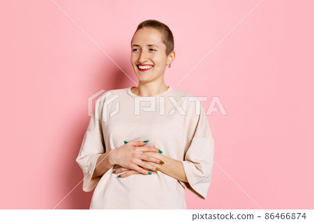 Half-length portrait of young woman, student with short hair in white t-shirt laughing isolated on pink background. Concept of emotions, studying, ad Half-length portrait of young woman, student with short hair in white t-shirt laughing isolated on pink background. Concept of emotions, studying, ad 86466874