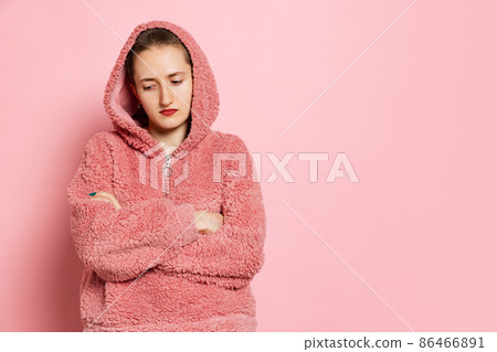 Sad young woman, student with short hair in pearch color hoodie isolated on pink background. Concept of emotions, studying, ad Sad young woman, student with short hair in pearch color hoodie isolated on pink background. Concept of emotions, studying, ad 86466891