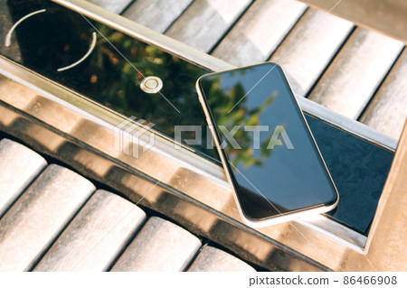 Charging smartphone using wireless charging pad on smart bench with free city charger and wifi. Wireless charging technology. Tourist tips Charging smartphone using wireless charging pad on smart bench with free city charger and wifi. Wireless charging technology. Tourist tips 86466908