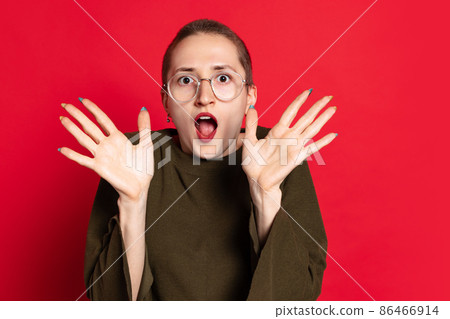 Shocked, surprised woman, student with short hair in dark sweater standing with open mouth isolated on red background. Concept of emotions, studying, ad 86466914