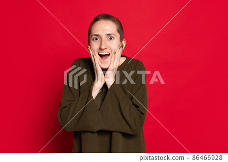 Young surprised woman, student with short hair in dark sweater isolated on red background. Concept of emotions, studying, ad Young surprised woman, student with short hair in dark sweater isolated on red background. Concept of emotions, studying, ad 86466928