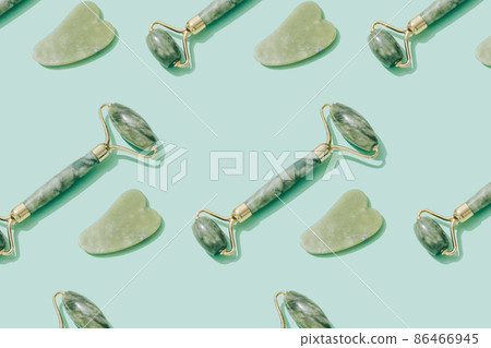 Pattern made with jade gua sha tool and facial roller on pastel green background. Facial massage kit for lifting massage therapy made from natural stones, personal skin care anti-aging tools 86466945