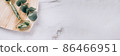 Banner with gua sha jade facial roller on white marble table background with copy space. Facial massage kit for lifting massage therapy made from natural stones, personal skin care tools 86466951