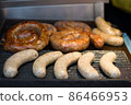 Closeup view of fresh delicious grilled and fried bavarian sausages with sticks. Street food at local market of traditional festival, street food market vendor 86466953