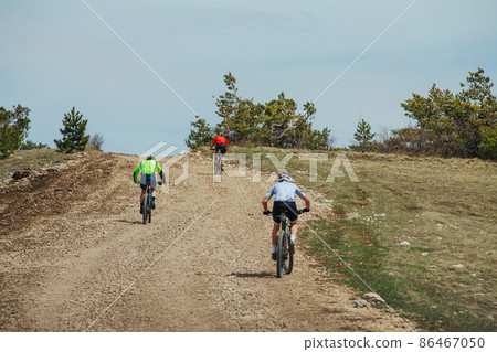 three athletes cyclists riding uphill on mountain bike 86467050