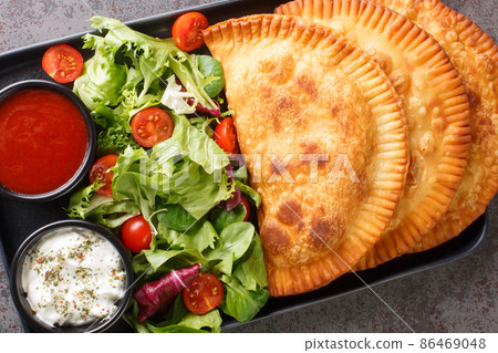 Chebureki is a national dish of Crimean Tatar cuisine maded with a single round piece of dough with meat filling close-up in a plate. Horizontal top view 86469048