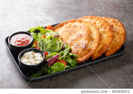 Chebureki is dish of Crimean Tatar cuisine served with fresh salad and sauces close-up in a plate. Horizontal Chebureki is dish of Crimean Tatar cuisine served with fresh salad and sauces close-up in a plate. Horizontal 86469052