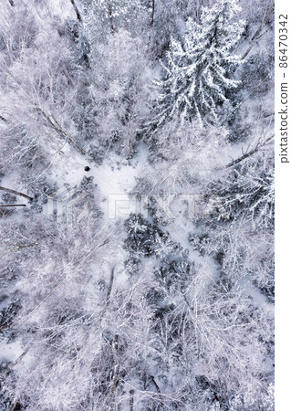Aerial of man in a beautiful winter snow covered forest 86470342