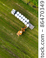 Tractor loading winter feed for livestock on a trailer 86470349