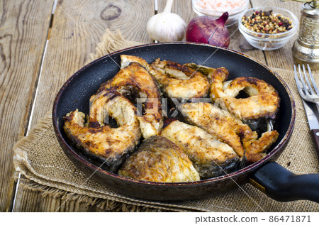 Old frying pan with fried fish on wooden table. 86471871