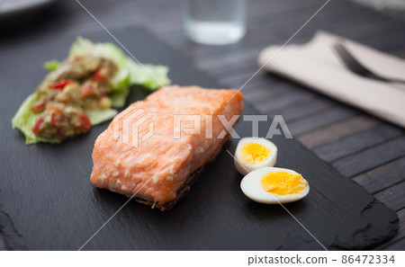 baked salmon fillet with homemade guacamole and quail eggs halves 86472334