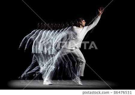 Young man, hip-hop dancer in action, motion isolated on dark background with sroboscope effect. Youth culture, hip-hop, movement, style and fashion, action. 86476531