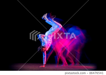 Freedom. Dynamic portrait of male hip-hop dancer dancing isolated on dark background in mixed neon light. Youth culture, hip-hop, movement, style and fashion, action. 86476541