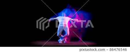 Dynamic portrait of male hip-hop dancer dancing isolated on dark background in mixed neon light. Youth culture, hip-hop, movement, style and fashion, action. 86476546