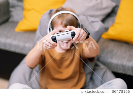 Teen boy with headphones and joystick playing video game console. Teen boy with headphones and joystick playing video game console. 86478196