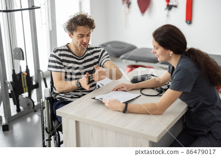 Rehabilitation specialist consulting man in wheelchair before training Rehabilitation specialist consulting man in wheelchair before training 86479017