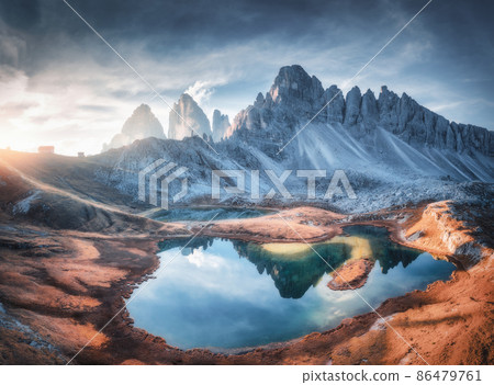 Aerial view of beautiful rocks, mountain lake, reflection in water and houses on the hill at sunset. Aerial view of beautiful rocks, mountain lake, reflection in water and houses on the hill at sunset. 86479761