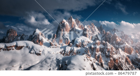 Beautiful mountain peaks in snow in winter at sunset. Dramatic landscape with high snowy rocks Beautiful mountain peaks in snow in winter at sunset. Dramatic landscape with high snowy rocks 86479787
