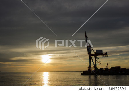 A container crane standing in the orange sunset on the quay of Kushiro Port at dusk A container crane standing in the orange sunset on the quay of Kushiro Port at dusk 86479894