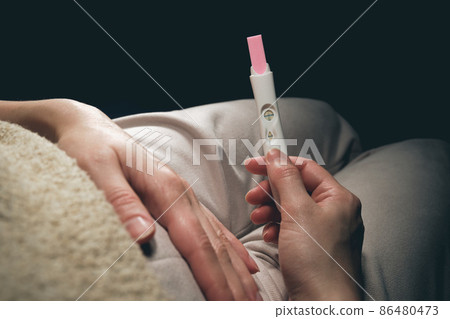 A woman sees a positive pregnancy test result. 86480473