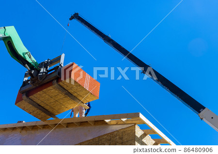 Builders are working on the roof covering it with plywood layer using professional hydraylic platform 86480906