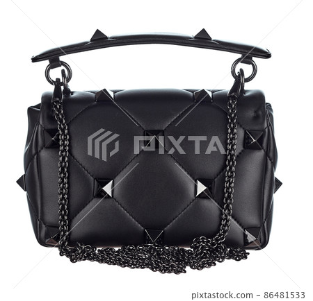 Handbag made of genuine leather in black color, decorated with chains and rivets in the shape of pyramids, with a metal clasp, isolated on a white background. Rear view.  86481533