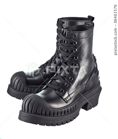 Pair of biker boots made of thick black leather, laced, with a high stylish sole made of automobile rubber with a reinforced front, isolated on a white background. Brutal shoes. 86481576