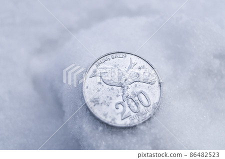 An old two hundred rupiah coin in the snow. The lost 200 rupiah coin. Money issued in 2003. Bank Indonesia. Soft focus, copy space 86482523