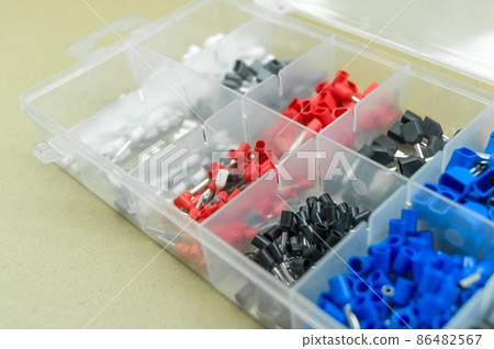 A set of colored crimp terminals for electrical wires. Crimping sleeves of different sizes. Plastic spare parts box for electrician. Toolbox. Selective focus 86482567