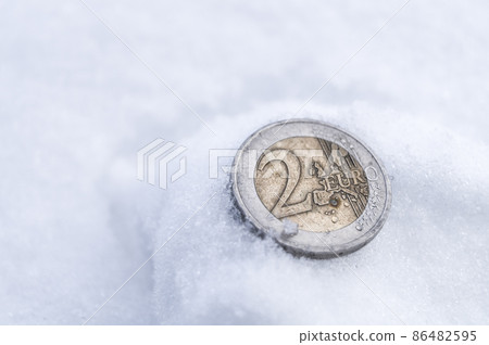 2 euro coin that fell on the snow. A lost old EU coin. Money issued in 2000. Soft focus, copy space 86482595